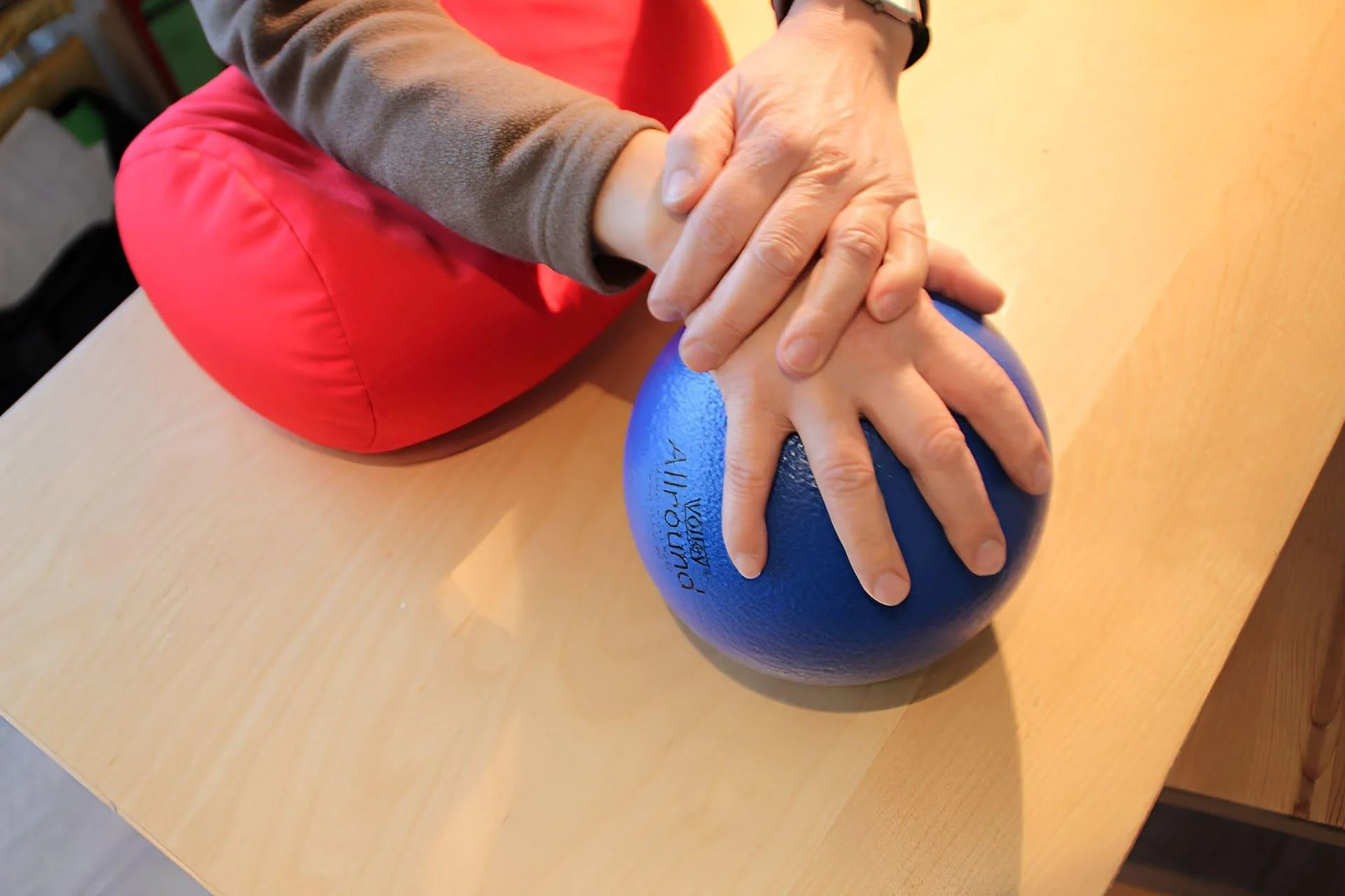 Hände bei einer Ergotherapie-Übung mit blauem Ball